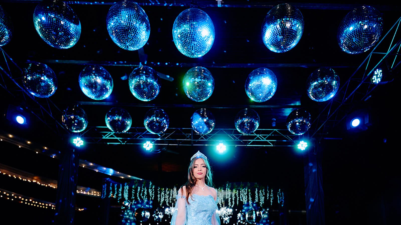 Quinceañera con corona bajo un techo de bolas de espejo en su fiesta de 15 años