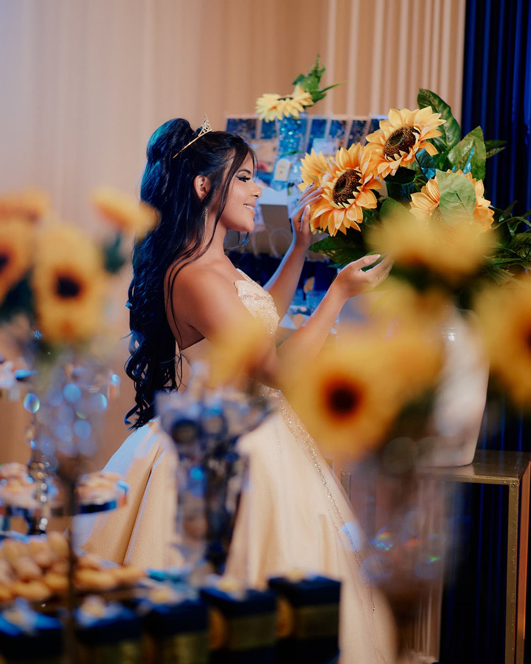 Quinceañera con vestido de gala junto a un arreglo de girasoles