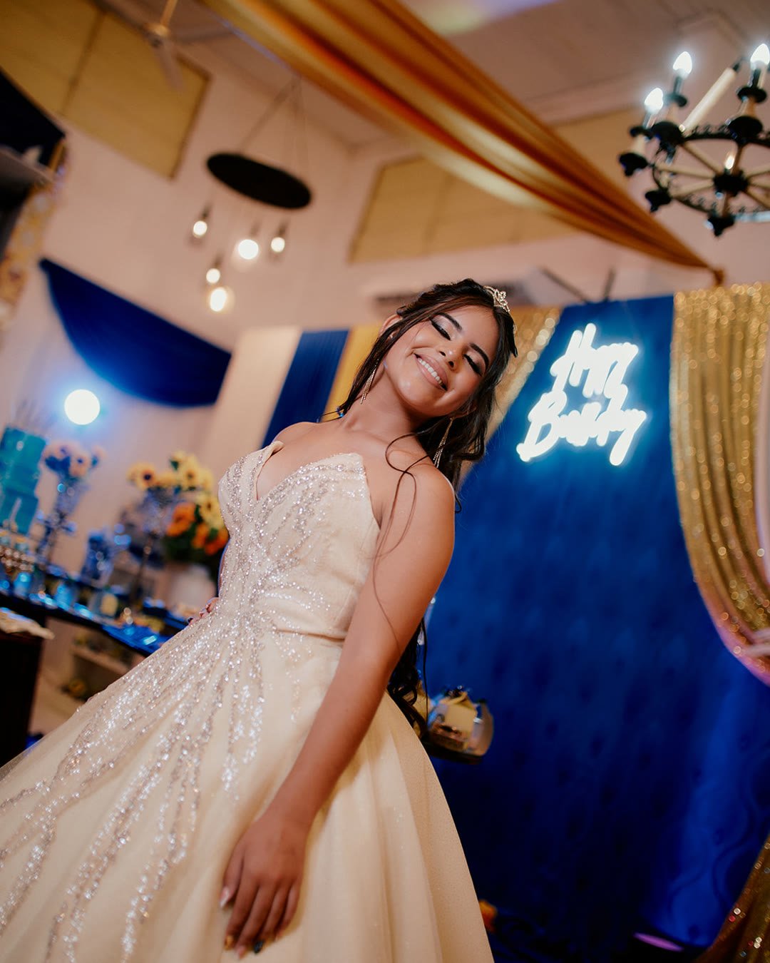 Quinceañera sonriendo con vestido de gala bordado en su fiesta