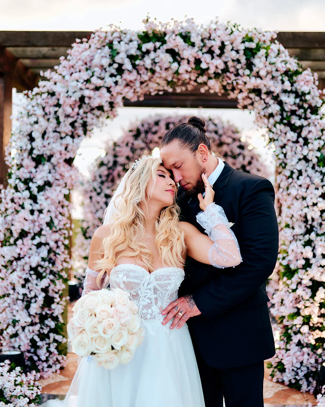 Novios abrazados bajo un arco de flores en una boda en Encarnaci&oacute;n
