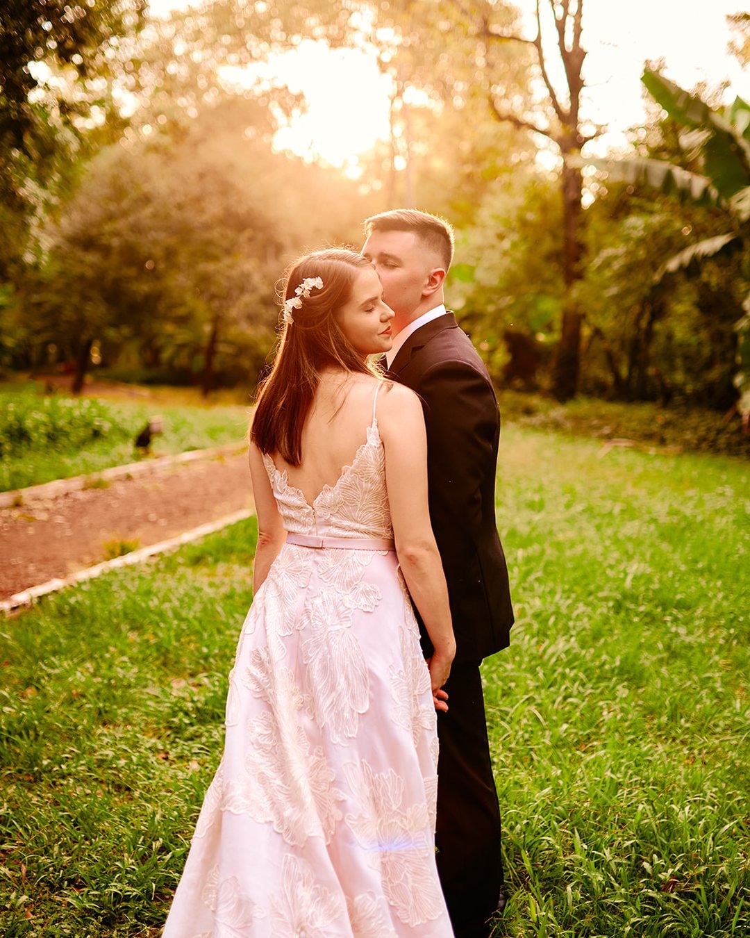 Novios caminando tomados de la mano por un sendero al atardecer