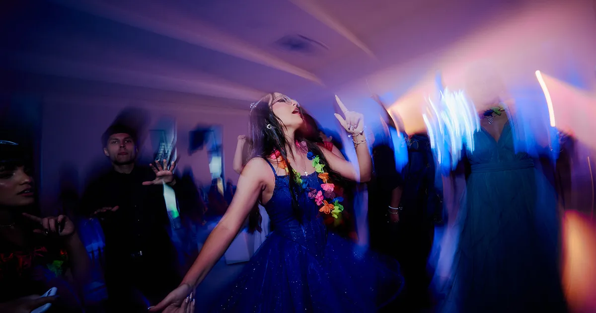 Quinceañera entrando al salón bajo esferas de espejo y luces de fiesta