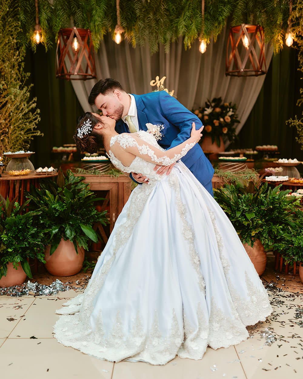 Novio inclinando a la novia para besarla frente a la decoración de la fiesta