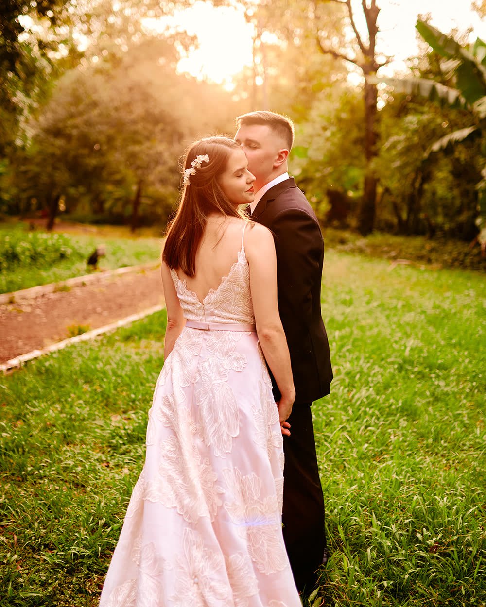 Novios abrazados en un jardín a la luz del atardecer