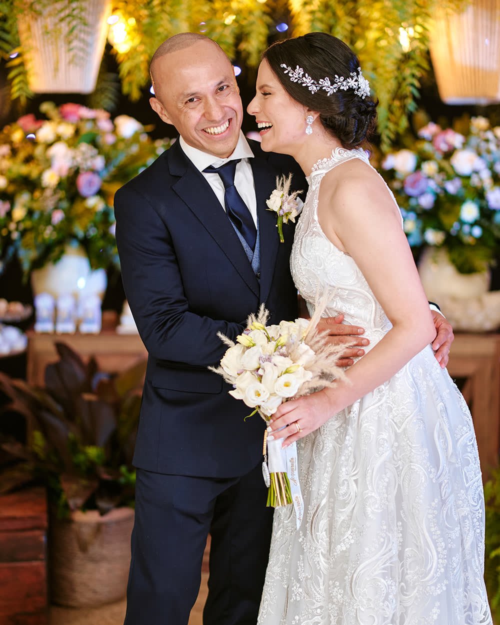 Novios riéndose juntos con un ramo de flores blancas