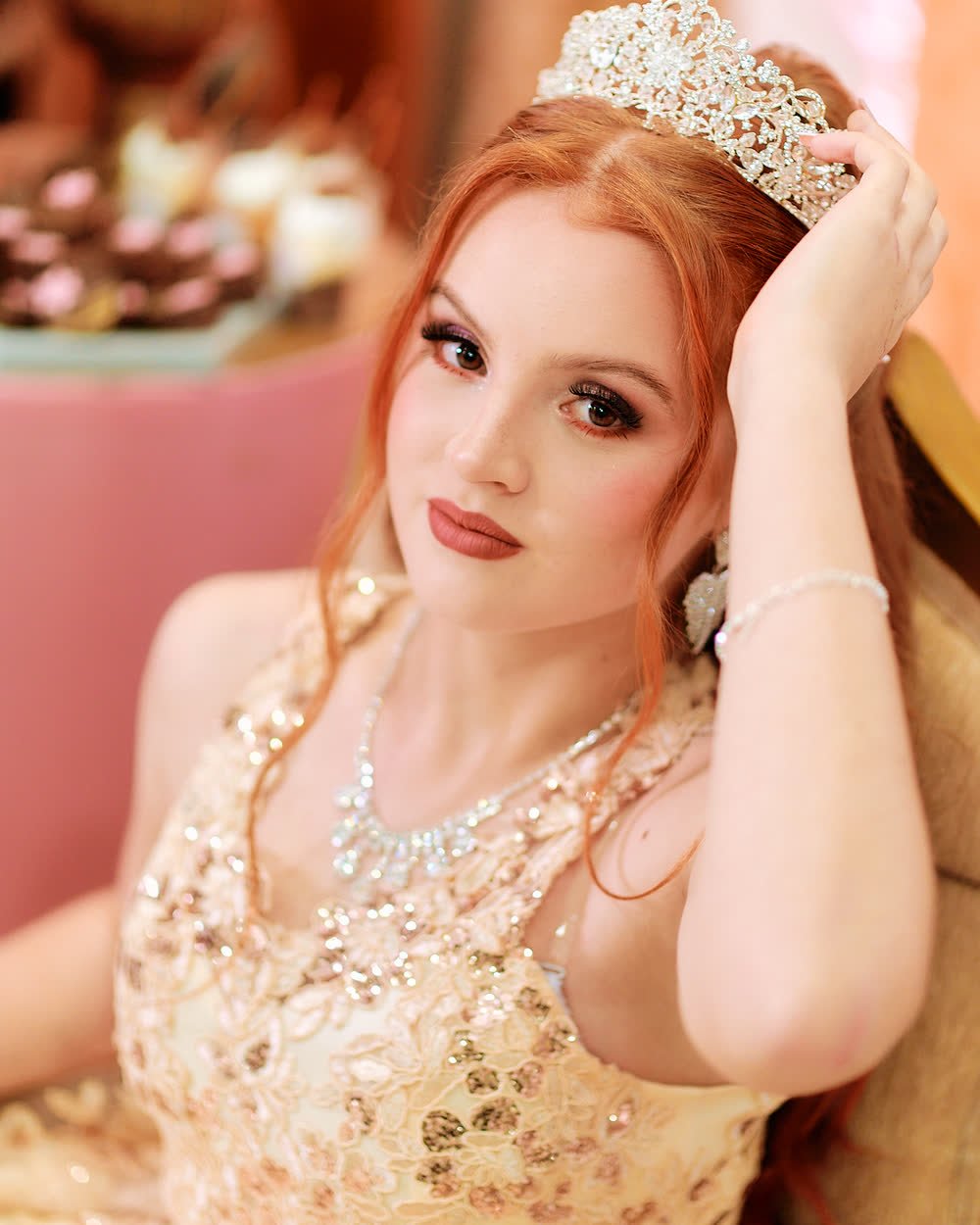 Retrato de una quinceañera pelirroja con corona y vestido dorado