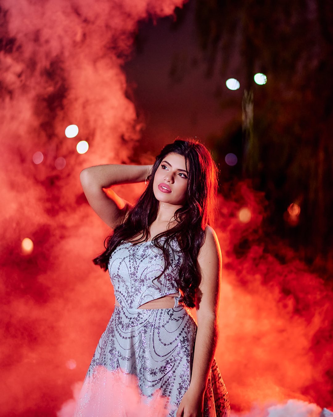 Sesión pre-XV con humo rojo de fondo, vestido plateado